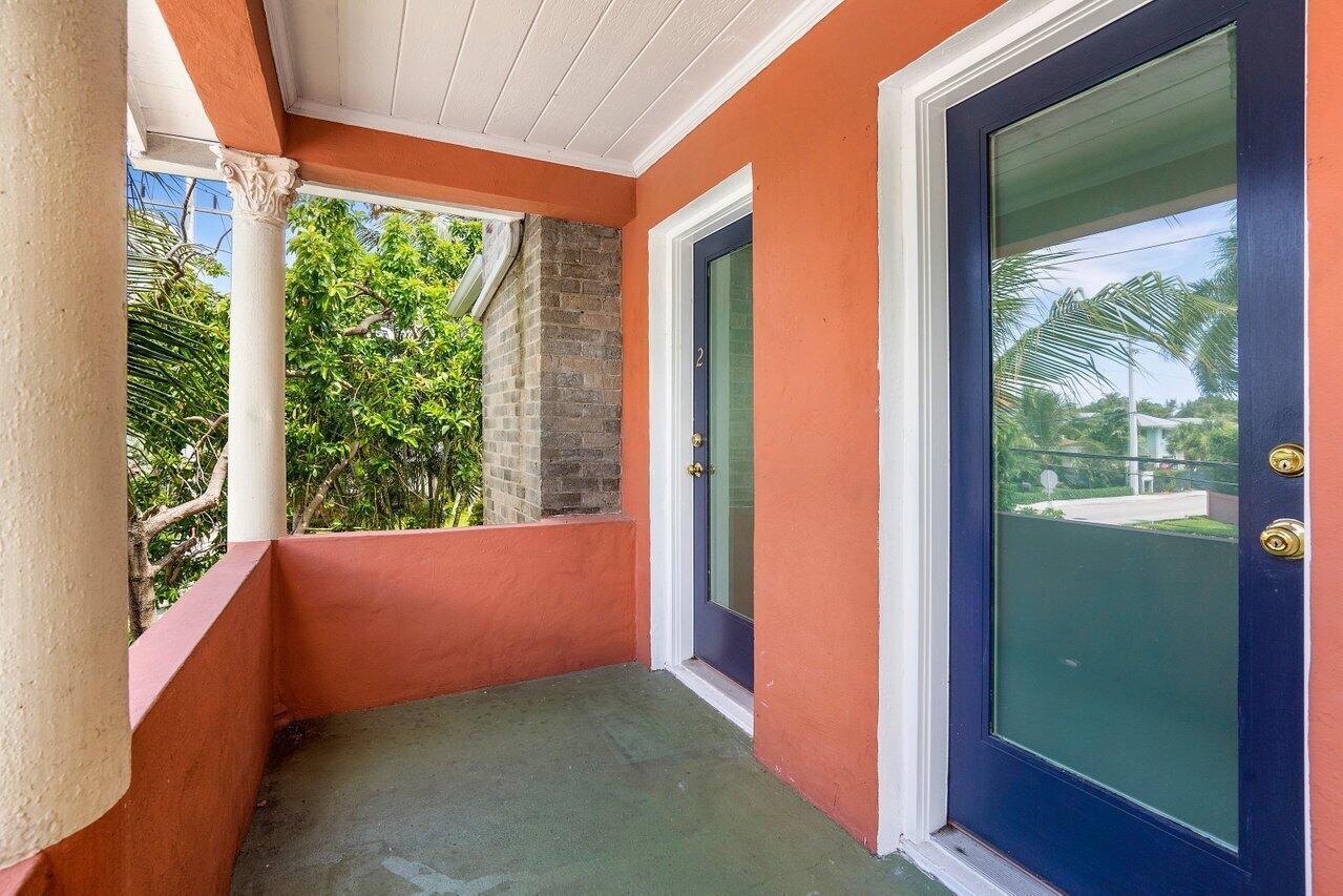 A covered porch with orange walls, a green floor, and two dark blue glass doors — 102 SE 7th Avenue # 2, Delray Beach FL 33483, DELRAY BEACH, FL