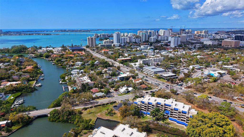 An aerial view shows a coastal city with a waterway, bridge, and surrounding residential buildings — 825 S OSPREY AVENUE UNIT 108, SARASOTA, FL
