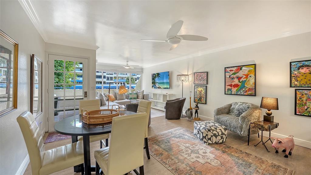 A living and dining area with light wood floors, a ceiling fan, and colorful wall art — 825 S OSPREY AVENUE UNIT 108, SARASOTA, FL