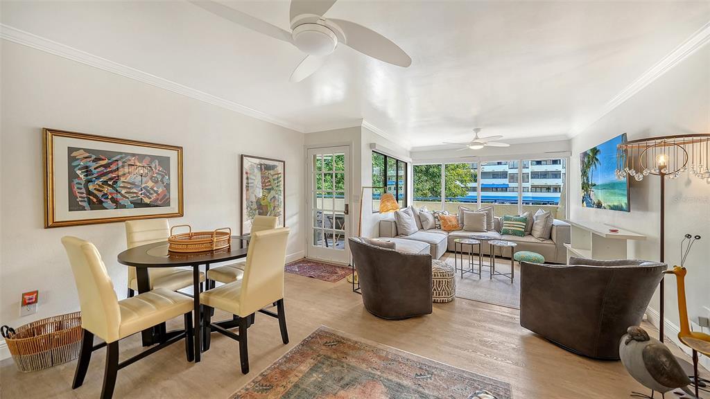 A living and dining area with light wood floors, a sectional sofa, and a table — 825 S OSPREY AVENUE UNIT 108, SARASOTA, FL