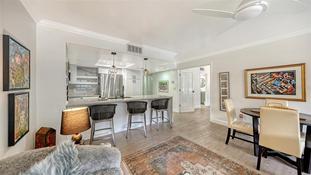 A kitchen with a breakfast bar and stools opens into a dining and living area — 825 S OSPREY AVENUE UNIT 108, SARASOTA, FL