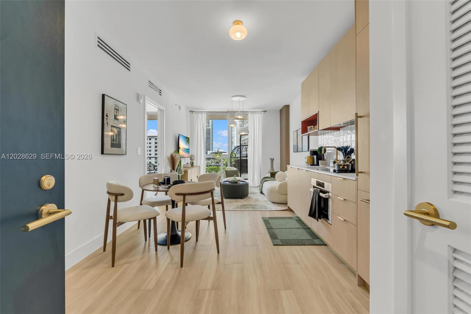 This open-concept apartment features a kitchen, dining area, and living space with light wood flooring — 90 32nd ST # 909, Miami FL 33127, MIAMI, FL
