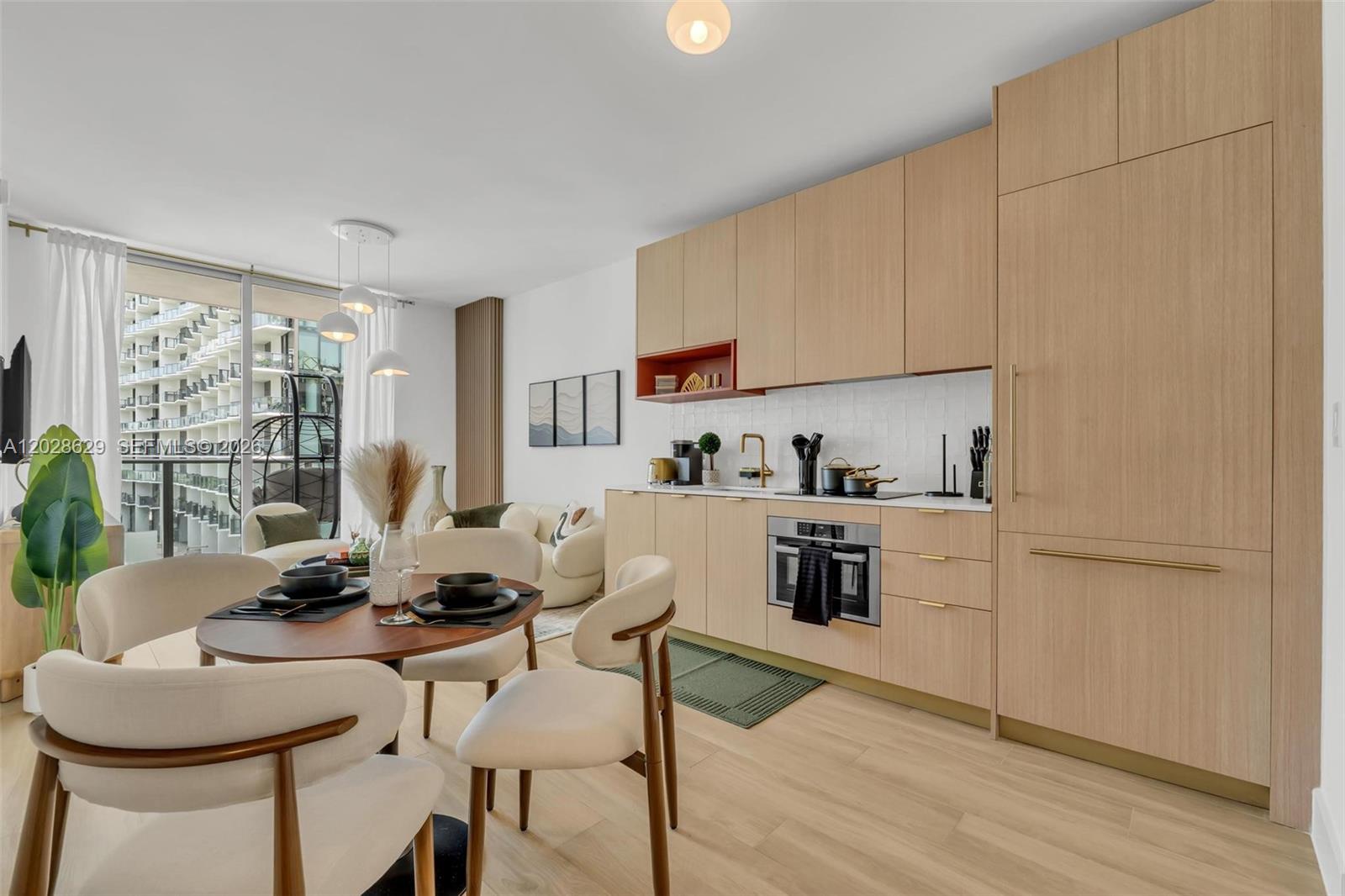 A modern kitchen features light wood cabinetry, white tile backsplash, and an adjacent dining area — 90 32nd ST # 909, Miami FL 33127, MIAMI, FL