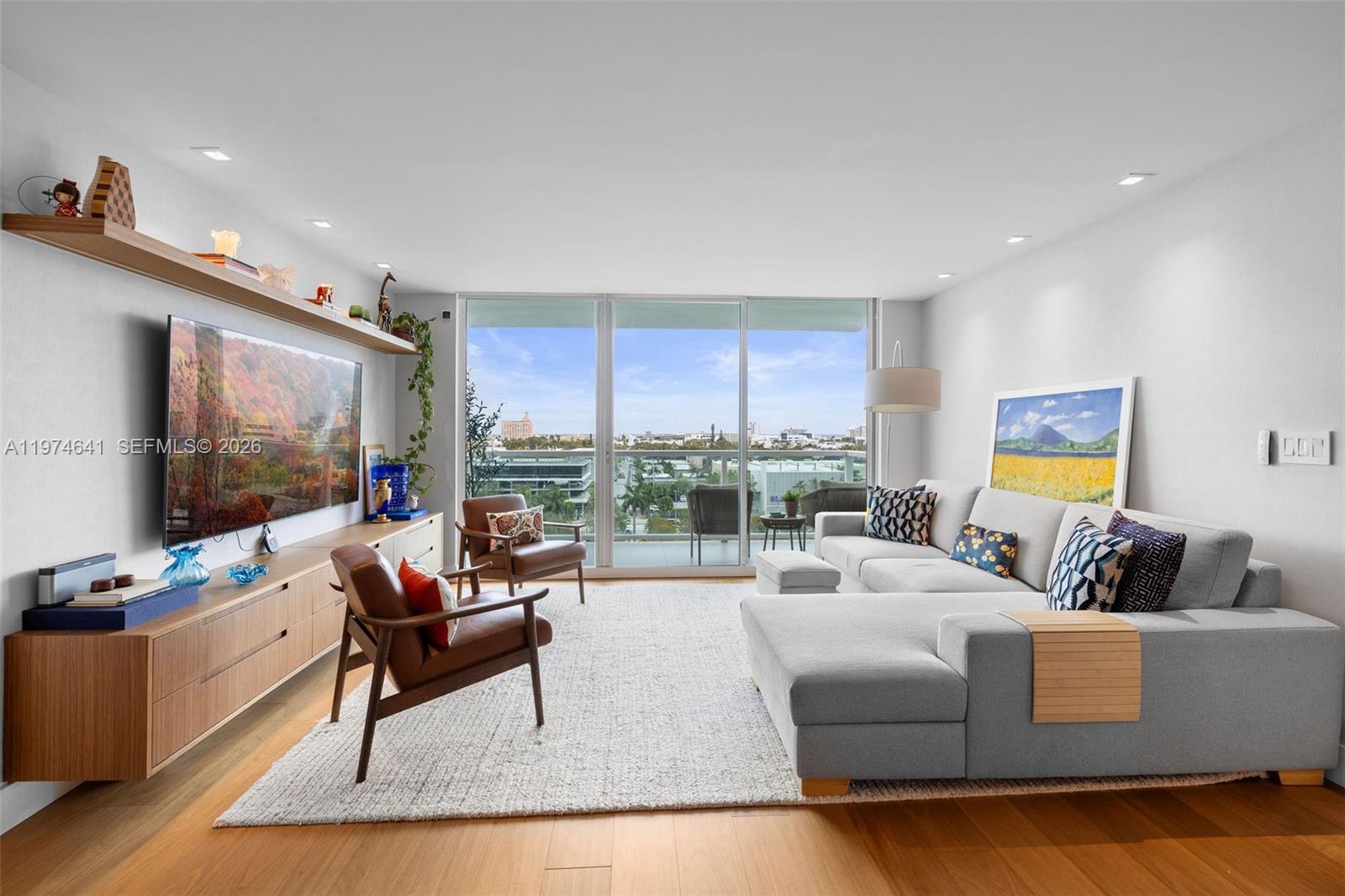 A modern living room features a grey sectional sofa, two leather armchairs, and floor-to-ceiling windows — 650 West Ave # 908, Miami Beach FL 33139, MIAMI BEACH, FL