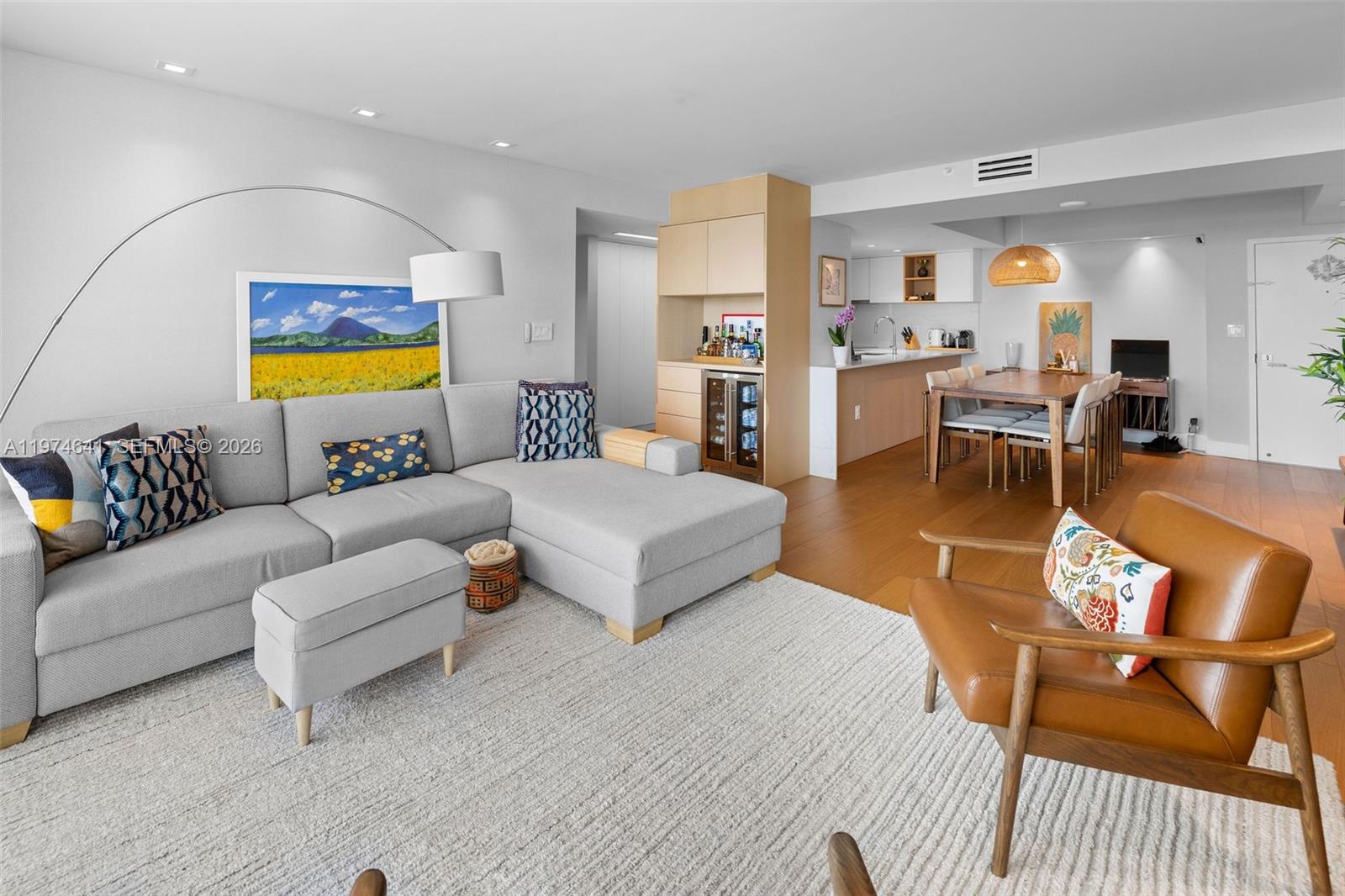 A living room with a gray sectional sofa, a leather armchair, and an open kitchen — 650 West Ave # 908, Miami Beach FL 33139, MIAMI BEACH, FL
