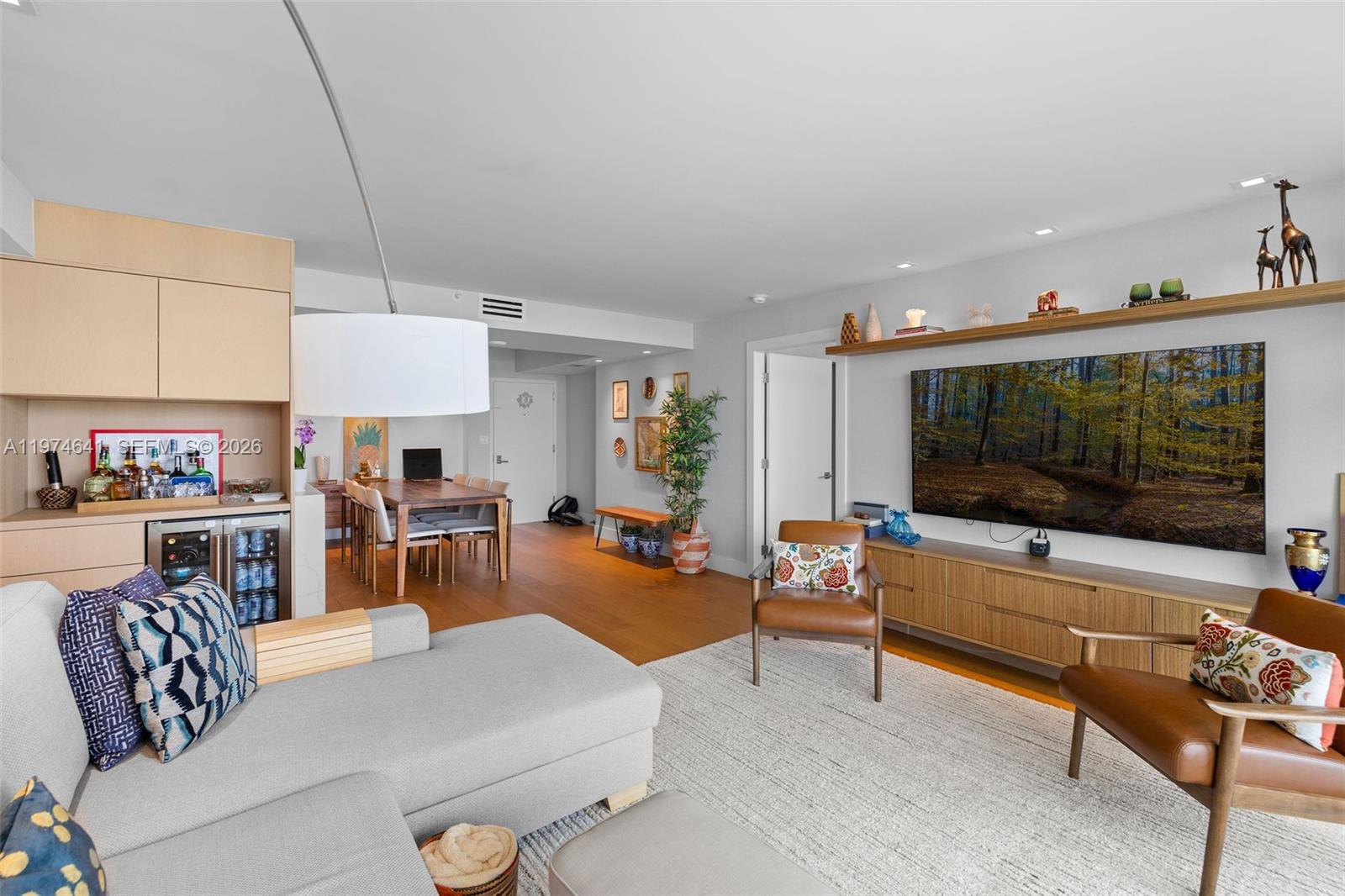 A living room features a grey sectional, two leather chairs, a television, and a dining area — 650 West Ave # 908, Miami Beach FL 33139, MIAMI BEACH, FL