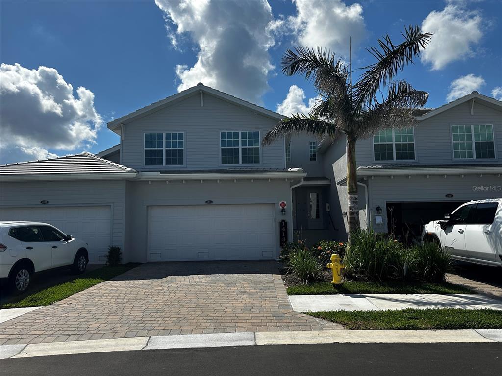 A two-story townhouse with a light gray exterior, a two-car garage, and a palm tree — 14132 POPPY FIELD LOOP UNIT 4021, PUNTA GORDA, FL