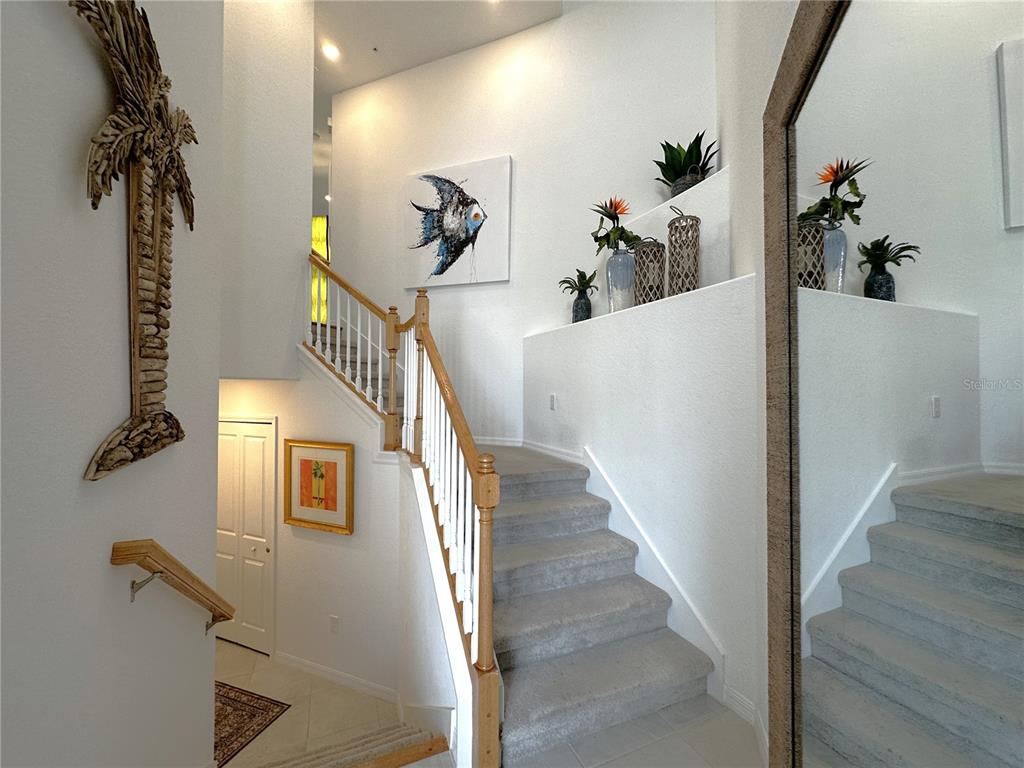 A carpeted staircase with a wooden railing leads to an upper level in a foyer — 14132 POPPY FIELD LOOP UNIT 4021, PUNTA GORDA, FL