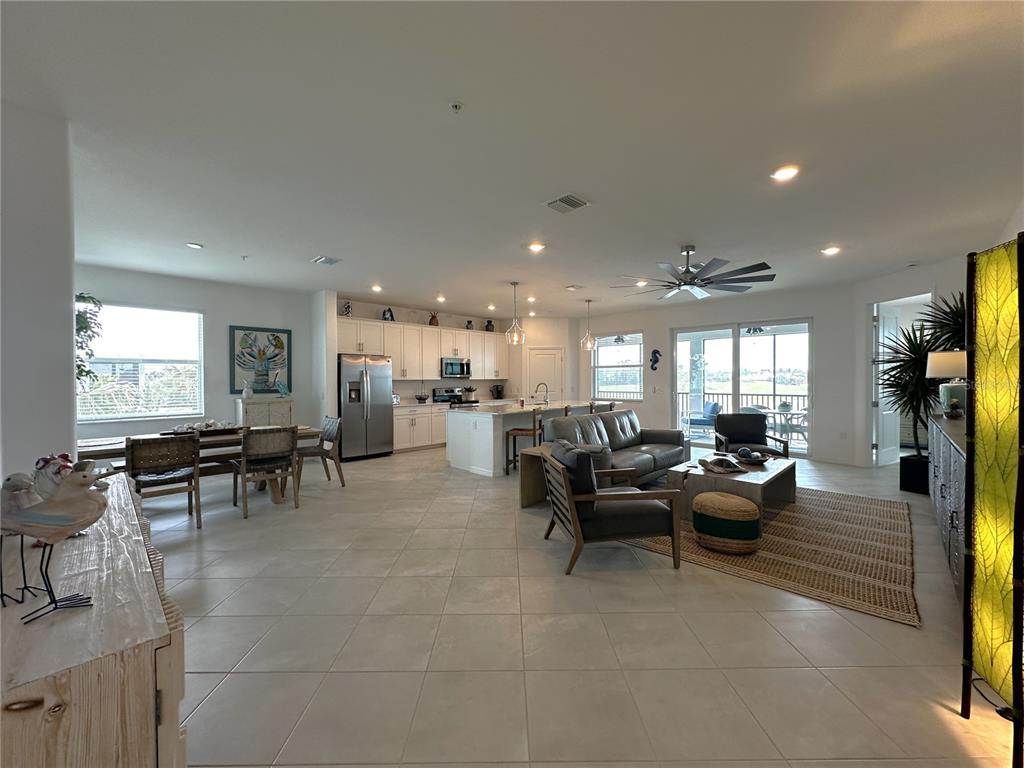 An open-concept living area features a kitchen with white cabinetry, a dining space, and tile flooring — 14132 POPPY FIELD LOOP UNIT 4021, PUNTA GORDA, FL