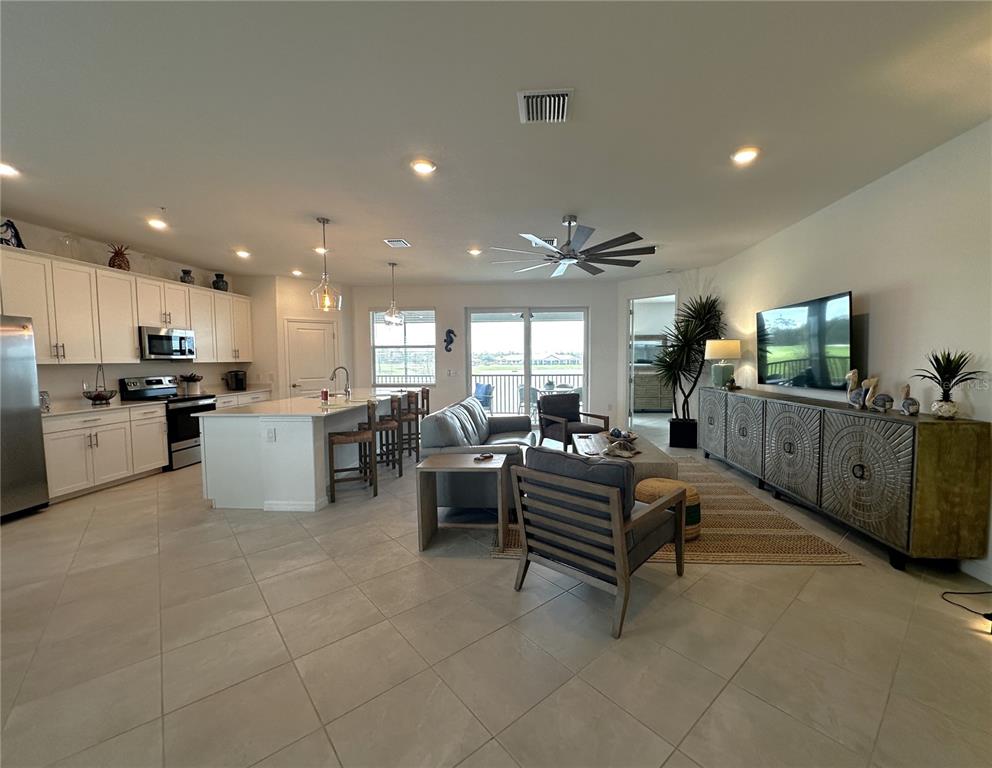 An open-concept kitchen and living area features white cabinetry, a kitchen island, and tile flooring — 14132 POPPY FIELD LOOP UNIT 4021, PUNTA GORDA, FL