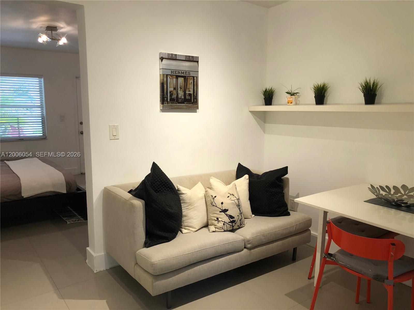 A beige sofa with black and white pillows sits in a room with a shelf — 911 Meridian Ave # 105, Miami Beach FL 33139, MIAMI BEACH, FL
