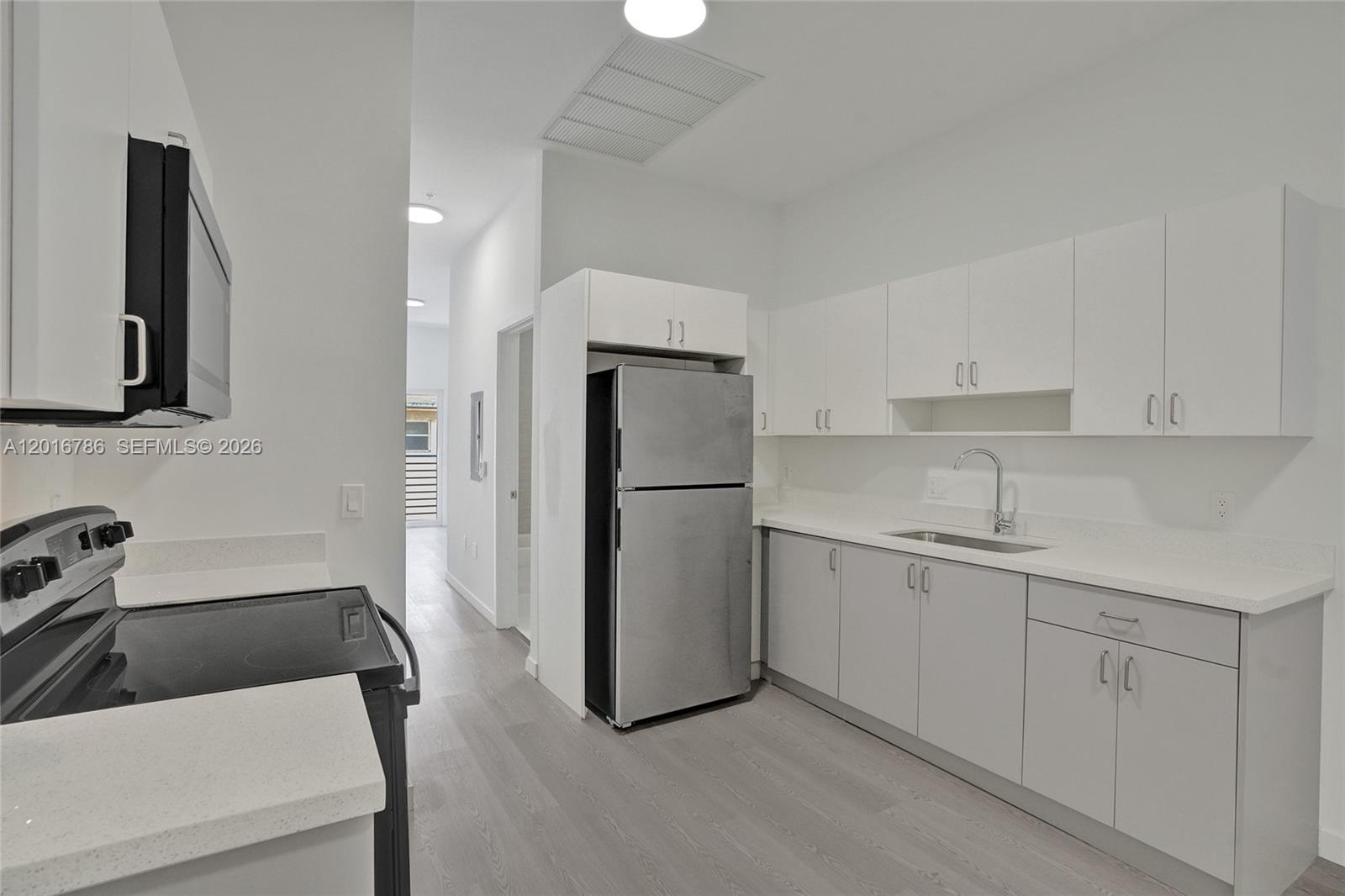 A modern kitchen features white upper cabinets, grey lower cabinets, and stainless steel appliances — 1567 NW 1st St # 9, Miami FL 33125, MIAMI, FL