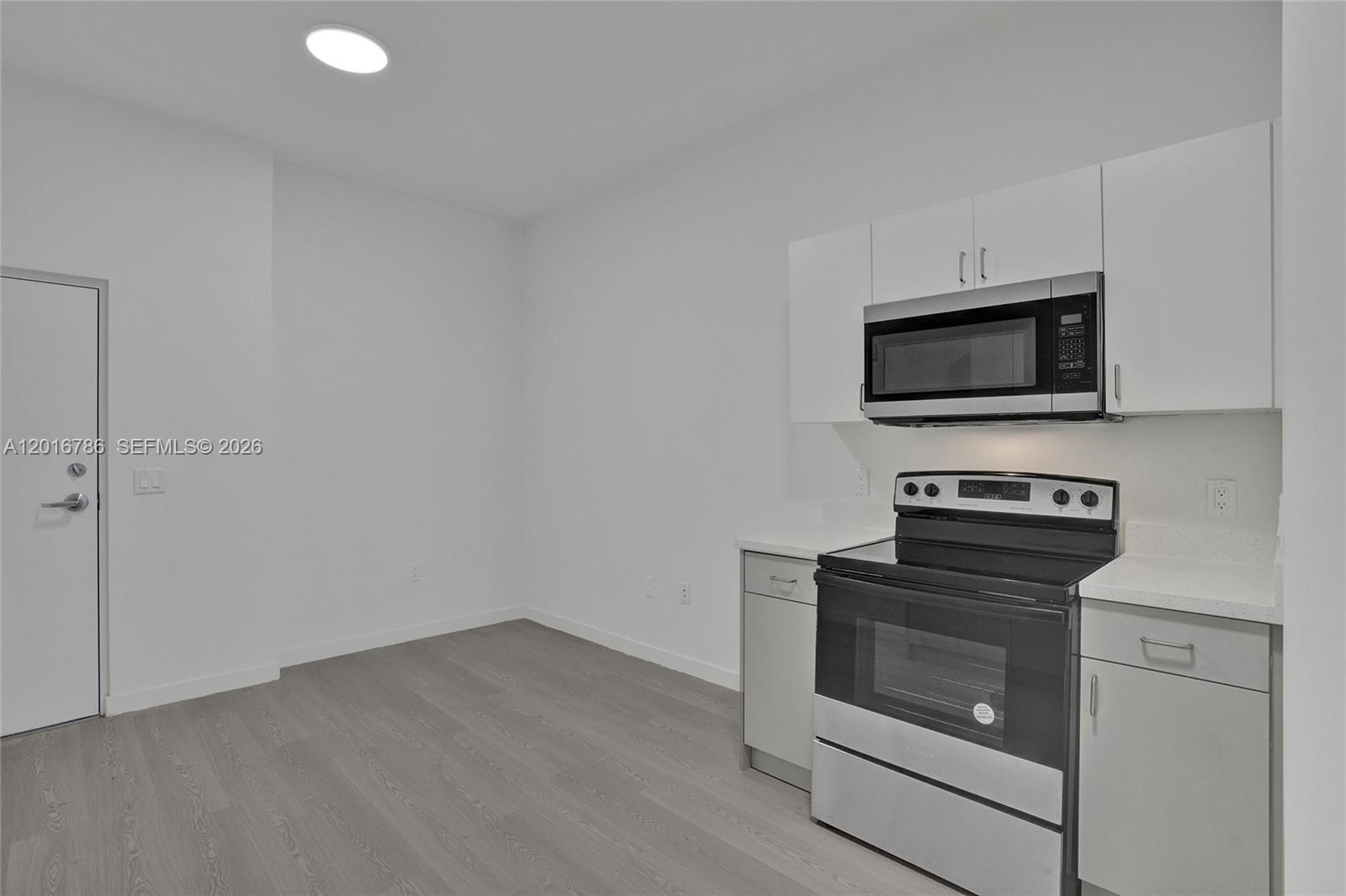 A kitchen area features white cabinets, stainless steel appliances, and light wood-look flooring — 1567 NW 1st St # 9, Miami FL 33125, MIAMI, FL