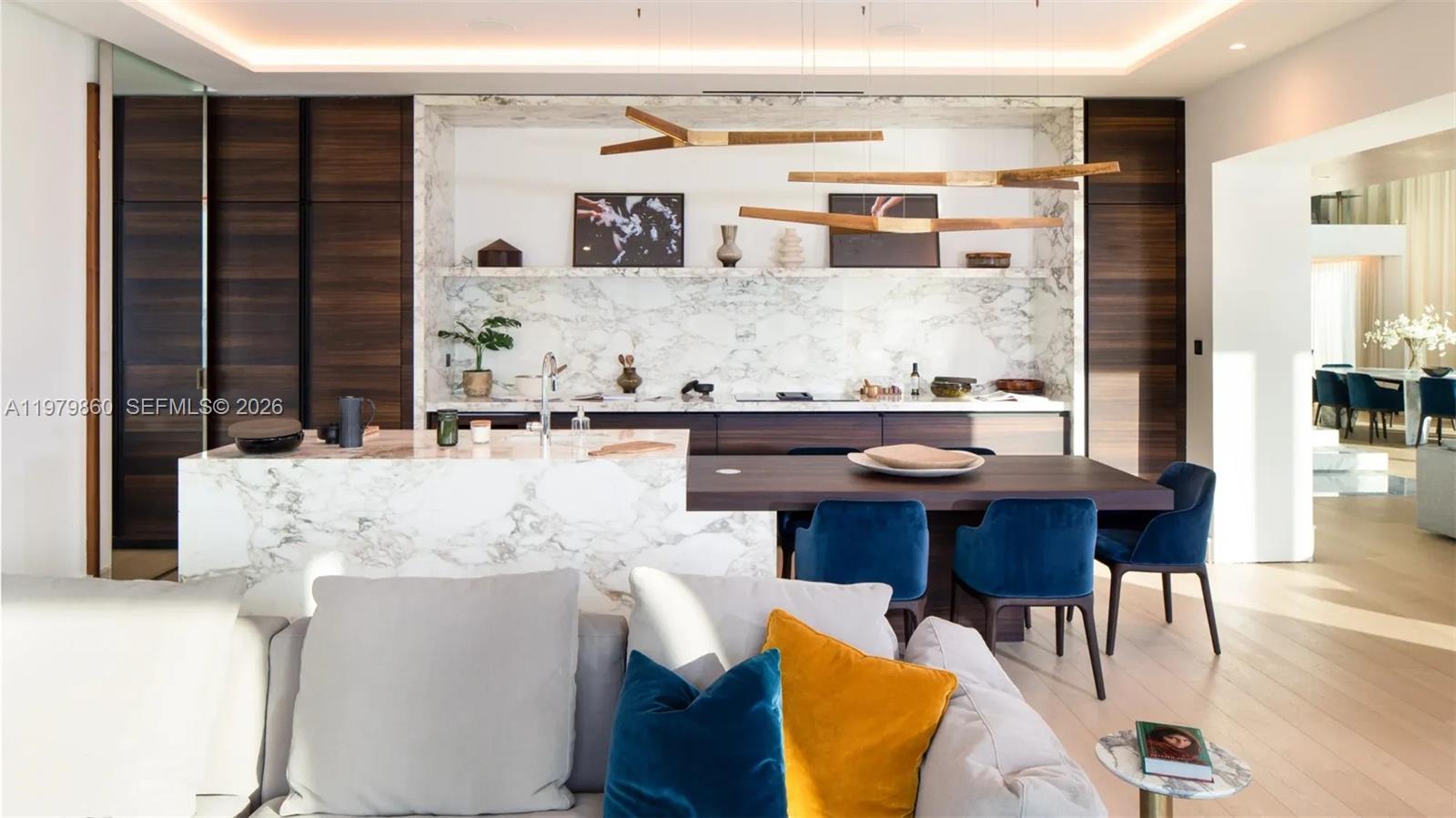 A modern kitchen features a marble island, dark wood cabinetry, and blue velvet dining chairs — 346 Marasi drive # 0, FL Dubai, FL