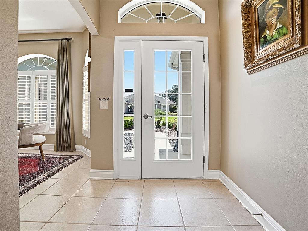 A tiled entryway features a white front door with glass panes and a transom window — 1969 HARTFORD PATH, THE VILLAGES, FL