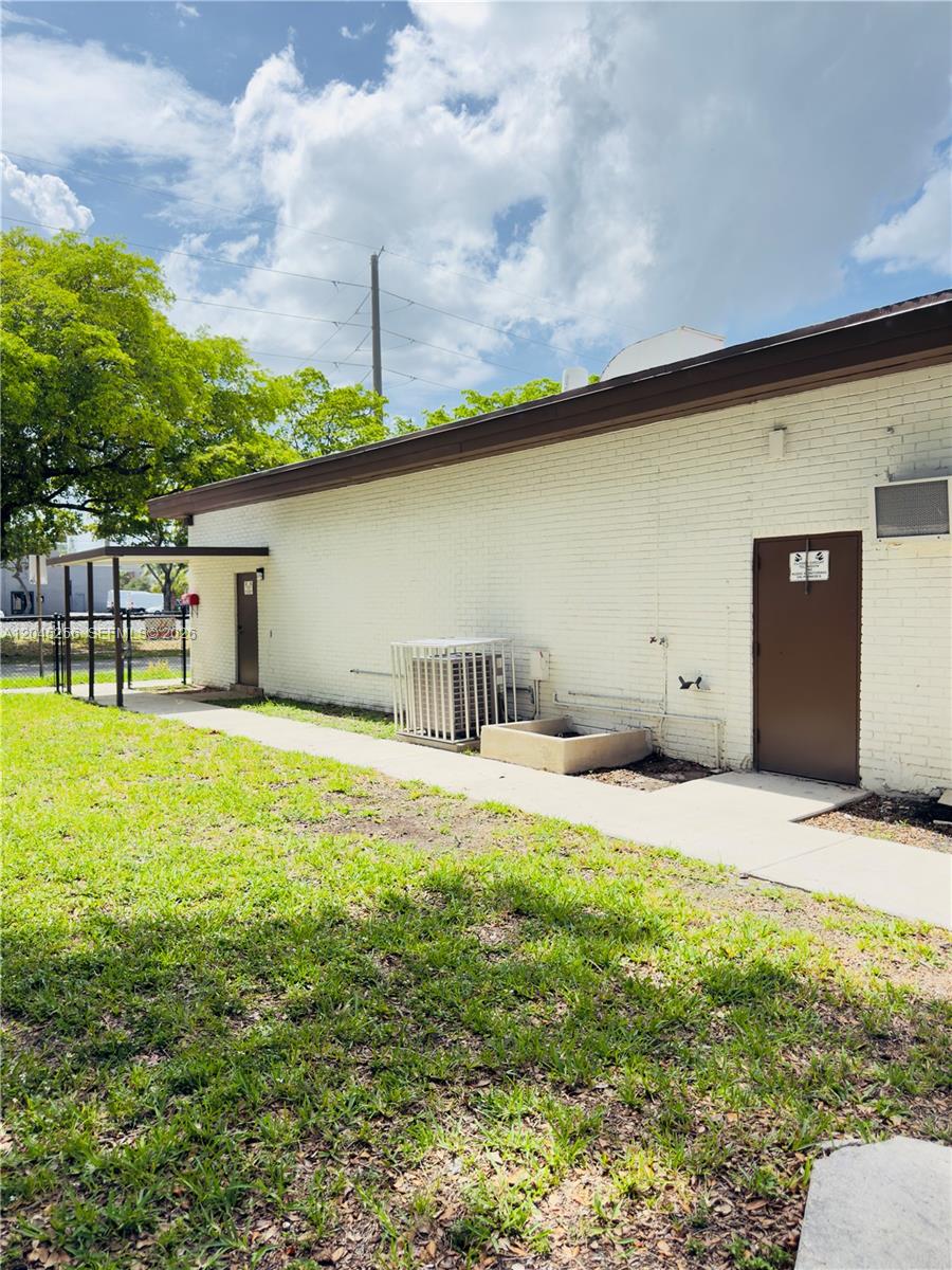 The exterior of a white brick building features two brown doors and an HVAC unit — 1601 S 21st Ave, Hollywood FL 33020, HOLLYWOOD, FL