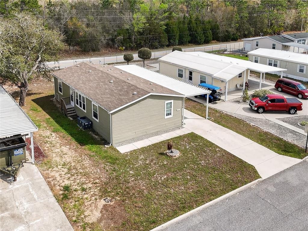An aerial view shows a light green manufactured home with a metal carport and driveway — 9925 SCEPTER AVENUE, BROOKSVILLE, FL