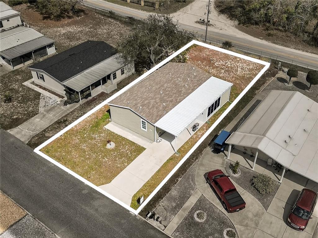 An aerial view shows a single-story house with a white carport and a fenced yard — 9925 SCEPTER AVENUE, BROOKSVILLE, FL