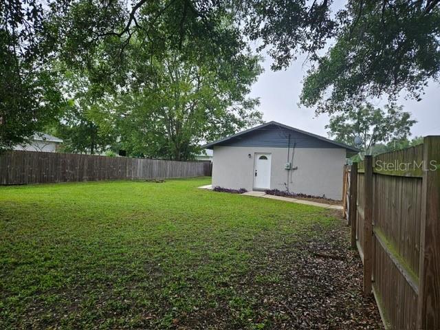 A detached garage sits in a grassy backyard enclosed by a wooden fence — 6881 NW 14TH AVENUE, OCALA, FL