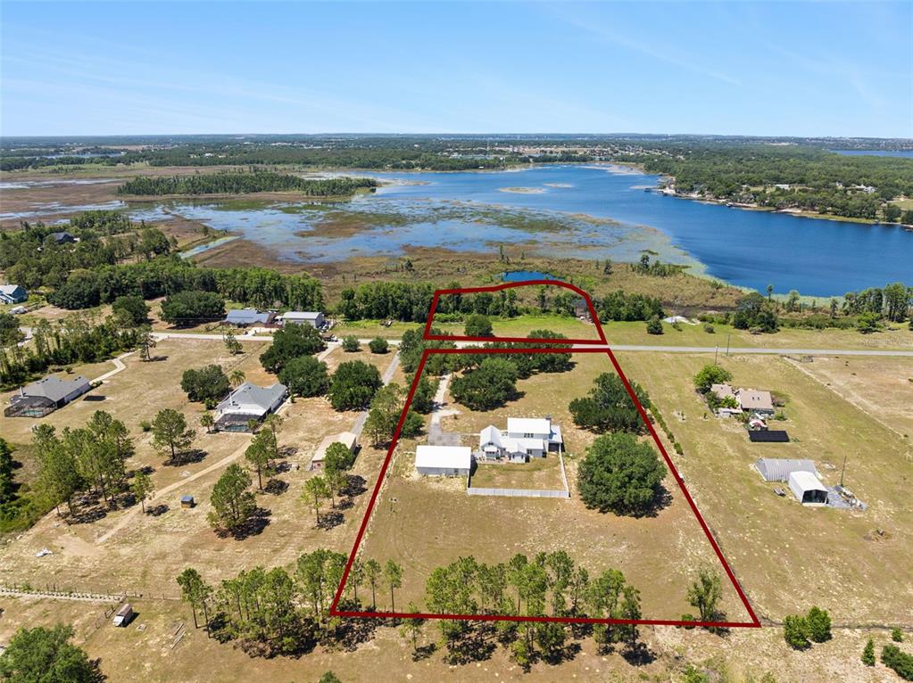 An aerial view shows a house and outbuilding on a large, fenced rural lot — 7956 LAKE NELLIE ROAD, CLERMONT, FL