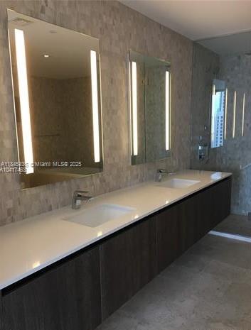 A modern bathroom features a long white vanity with two sinks and illuminated wall mirrors — 88 SW 7th St # 2603, Miami FL 33130, MIAMI, FL