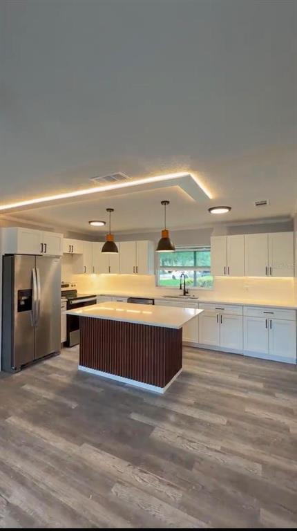 A modern kitchen features white cabinetry, a wood-slatted island, and recessed ceiling lighting — 1000 E DIXIE AVENUE, LEESBURG, FL