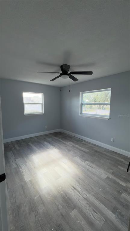 An empty bedroom features light gray walls, a ceiling fan, and wood-look laminate flooring — 1000 E DIXIE AVENUE, LEESBURG, FL