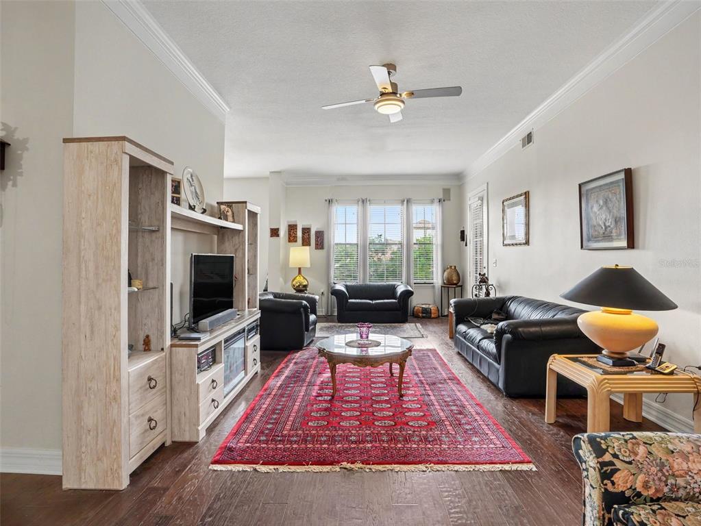 A living room features dark wood floors, a red area rug, and black leather furniture — 501 MIRASOL CIRCLE UNIT 313, CELEBRATION, FL