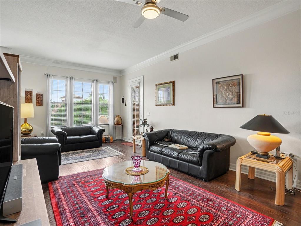 A living room features dark leather sofas, a red patterned rug, and a glass coffee table — 501 MIRASOL CIRCLE UNIT 313, CELEBRATION, FL