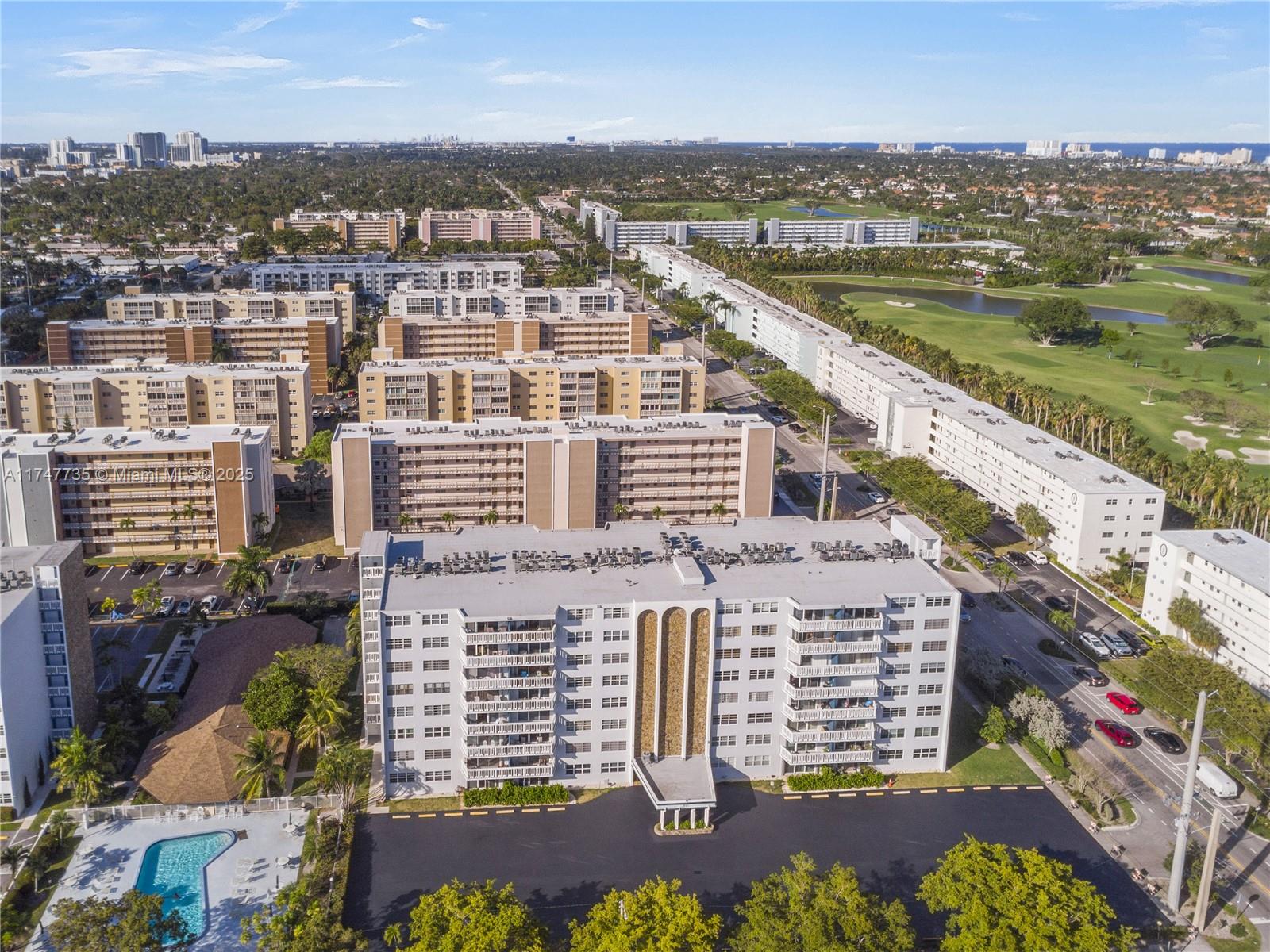 An aerial view shows a multi-story apartment building with a swimming pool and parking lot — 401 NE 14th Ave # 603, Hallandale Beach FL 33009, HALLANDALE BEACH, FL