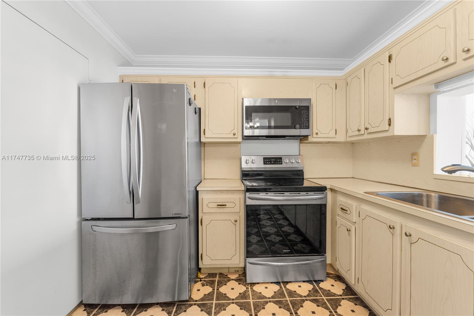 A kitchen features light-colored cabinets, stainless steel appliances, and patterned tile flooring — 401 NE 14th Ave # 603, Hallandale Beach FL 33009, HALLANDALE BEACH, FL