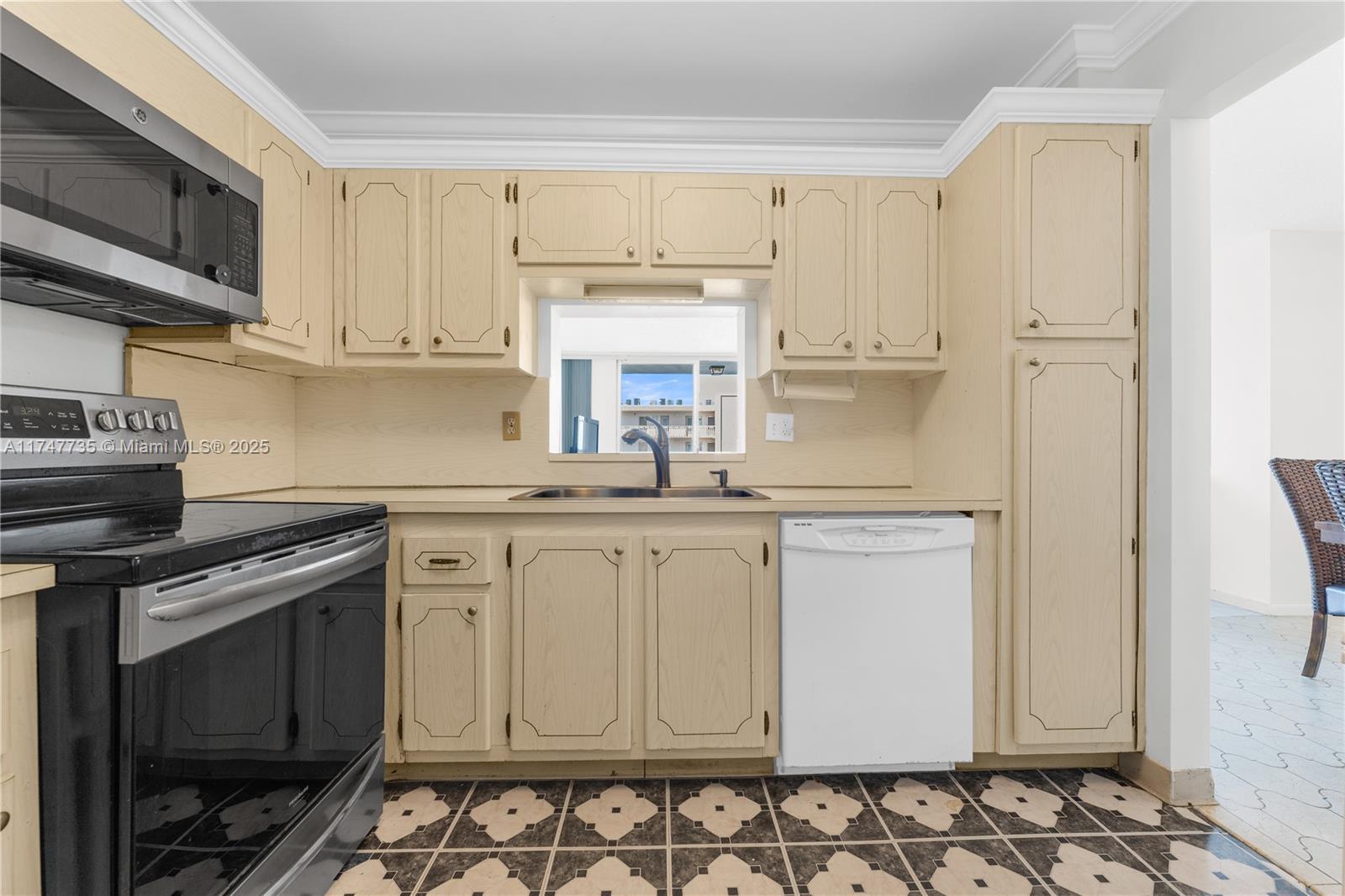 A kitchen features light-colored wooden cabinets, a black stove, a white dishwasher, and patterned flooring — 401 NE 14th Ave # 603, Hallandale Beach FL 33009, HALLANDALE BEACH, FL