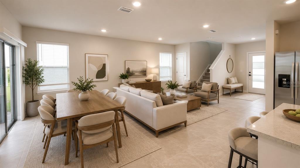 An open-concept living and dining area features light tile floors, neutral furniture, and large windows — 1965 BRANCHED OAK ROAD, ST CLOUD, FL