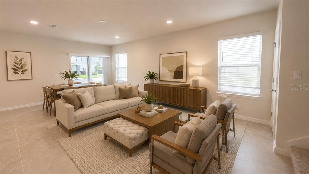 A living room with light-colored tile floors, a beige sofa, two armchairs, and a dining area — 1965 BRANCHED OAK ROAD, ST CLOUD, FL
