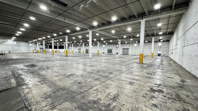 A large, empty industrial warehouse space features a concrete floor and multiple support columns — MIAMI, FL