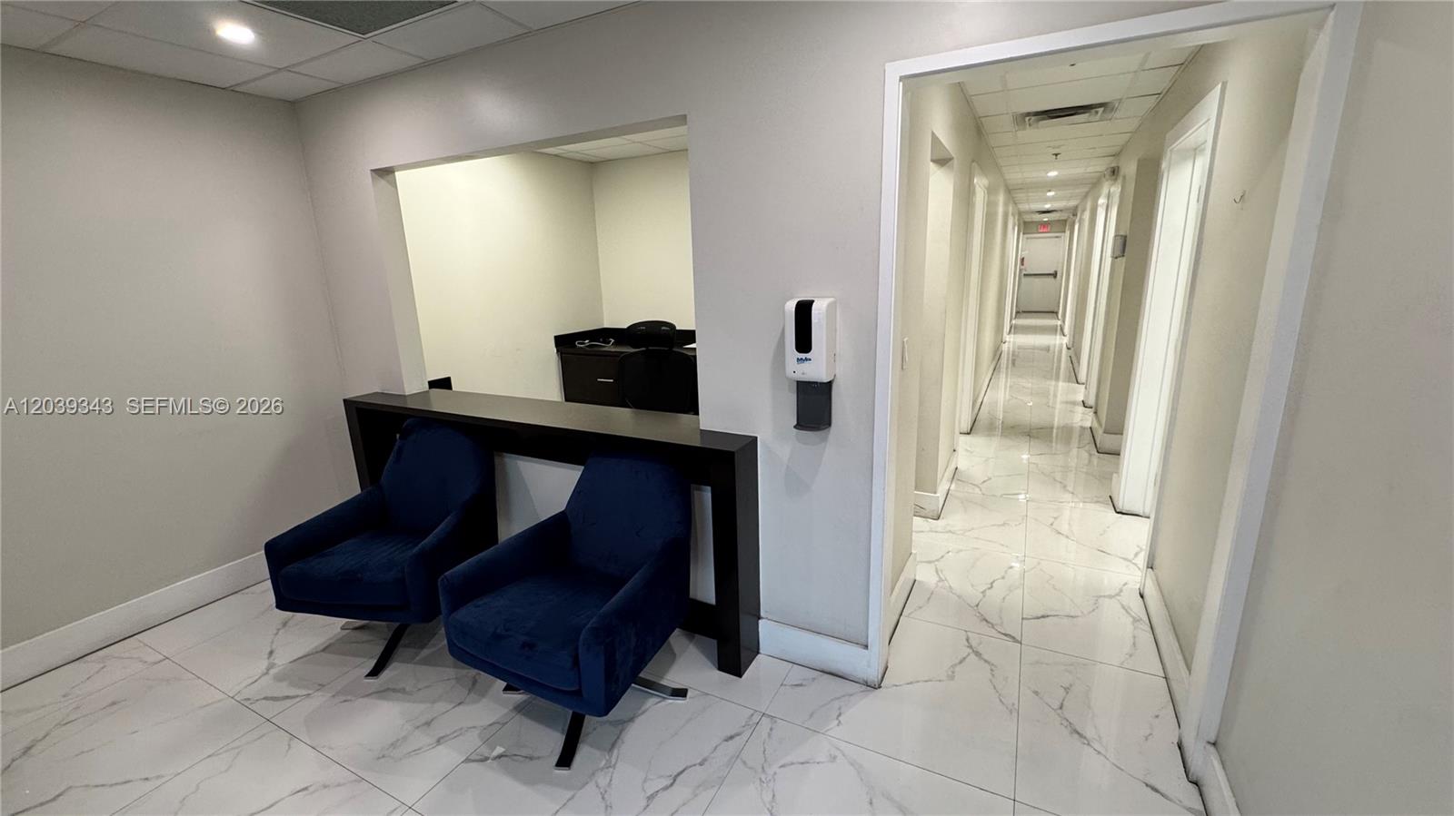 A waiting area features two blue chairs, a dark console table, and a tiled hallway — MIAMI, FL