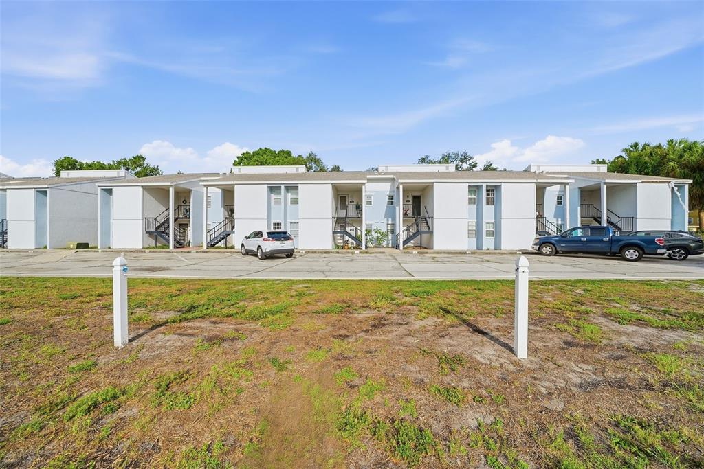 A two-story apartment building with a parking lot and a grassy foreground — 3821 N OAK DRIVE UNIT J21, TAMPA, FL