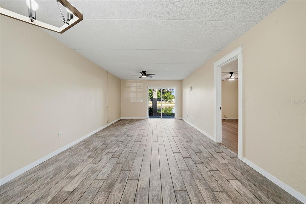 A living room with light-colored walls, wood-look tile flooring, a ceiling fan, and sliding doors — 3821 N OAK DRIVE UNIT J21, TAMPA, FL