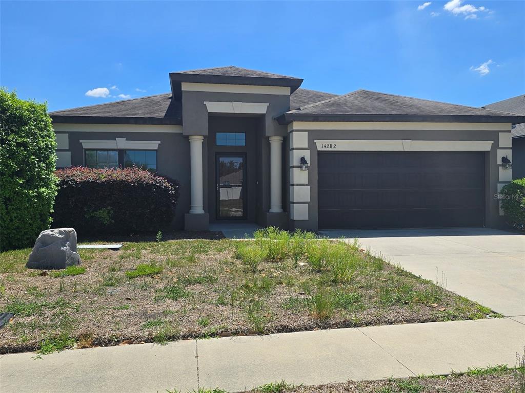 A single-story house with a dark gray exterior, white columns, and a two-car garage — 14282 SALTBY PLACE, SPRING HILL, FL