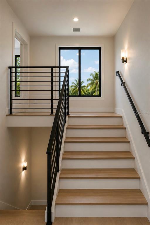A staircase with light wood treads and black metal railings leads to a landing with windows — 3904 DANA SHORES DRIVE, TAMPA, FL
