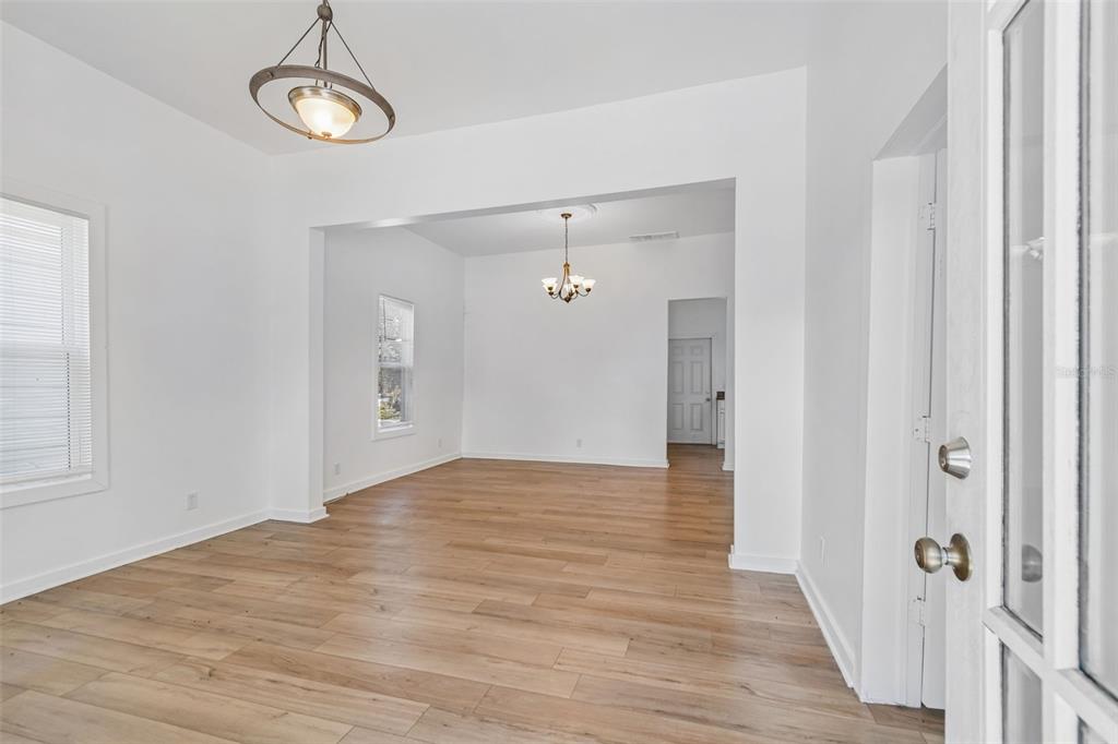 An interior view shows a living area with light wood flooring and two hanging chandeliers — 2601 N 19TH STREET, TAMPA, FL