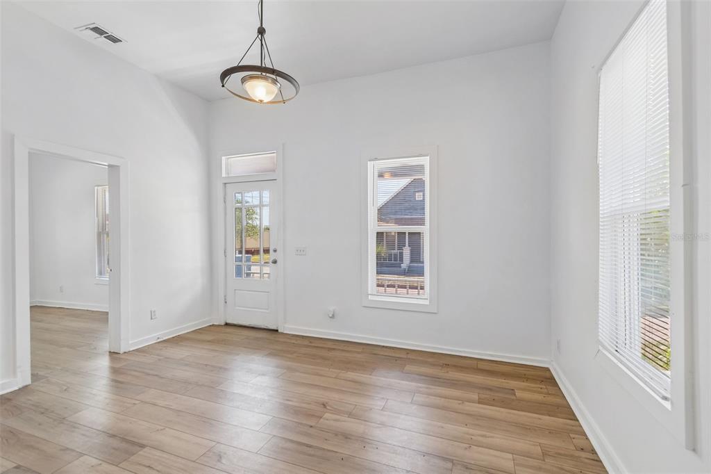 An empty room features light wood-look flooring, white walls, a pendant light, and a door — 2601 N 19TH STREET, TAMPA, FL