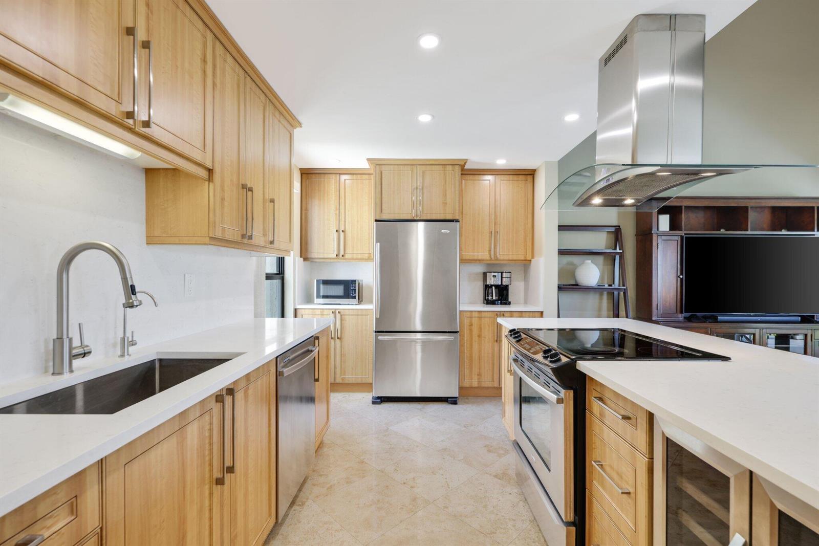 A modern kitchen features light wood cabinets, stainless steel appliances, and white quartz countertops — 800 Greensward Court # I, Delray Beach FL 33445, DELRAY BEACH, FL