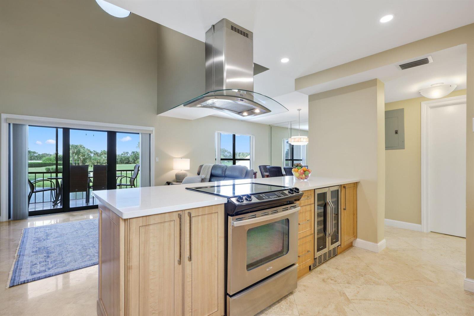 A kitchen island with a stainless steel range and hood overlooks a living area — 800 Greensward Court # I, Delray Beach FL 33445, DELRAY BEACH, FL