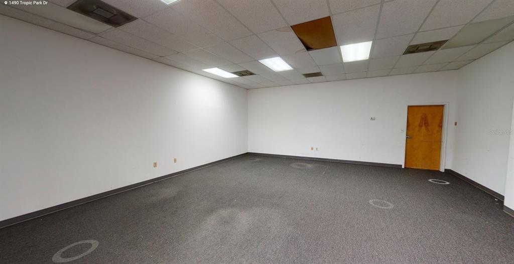 An empty office room features white walls, gray carpet, and a drop ceiling with lights — 1400 TROPIC PARK DRIVE UNIT 1490, SANFORD, FL