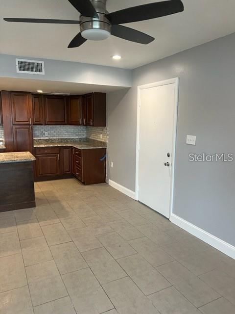 A kitchen with dark wood cabinets, granite countertops, and tile flooring opens to a doorway — 5123 TOPAZ LANE UNIT 204G, NEW PORT RICHEY, FL