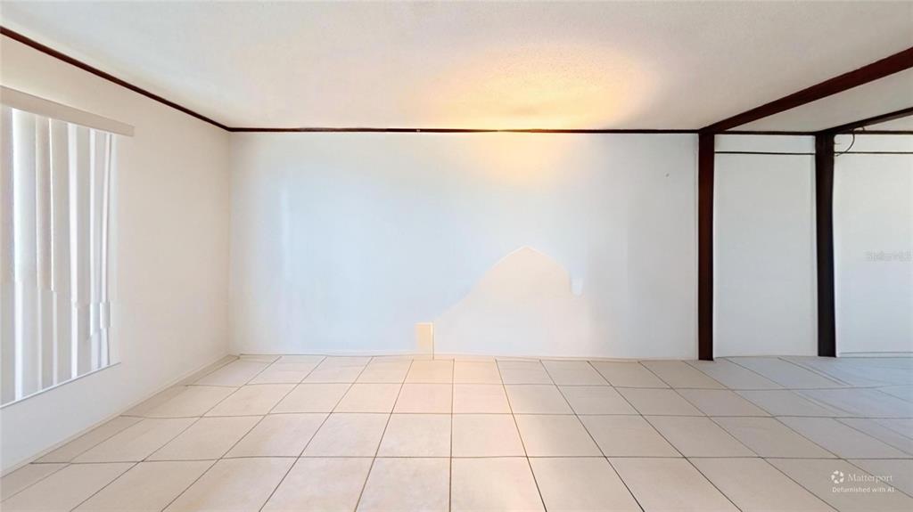 An empty room features white walls, a tiled floor, and a window with vertical blinds — 395 BACARDI DRIVE, MERRITT ISLAND, FL