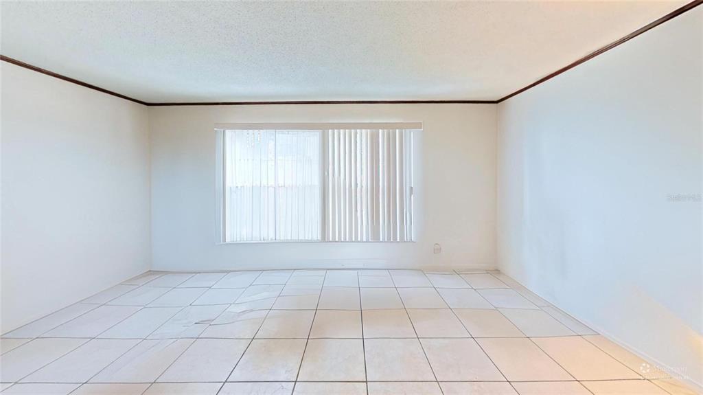 An empty room with white walls, large windows with vertical blinds, and light-colored floor tiles — 395 BACARDI DRIVE, MERRITT ISLAND, FL