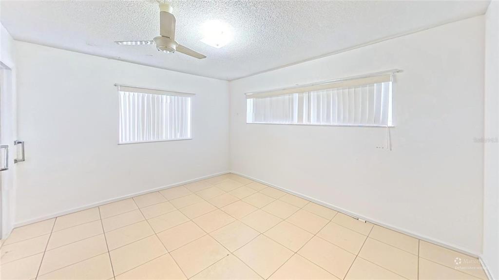 An empty room with white walls, tile flooring, a ceiling fan, and two windows — 395 BACARDI DRIVE, MERRITT ISLAND, FL