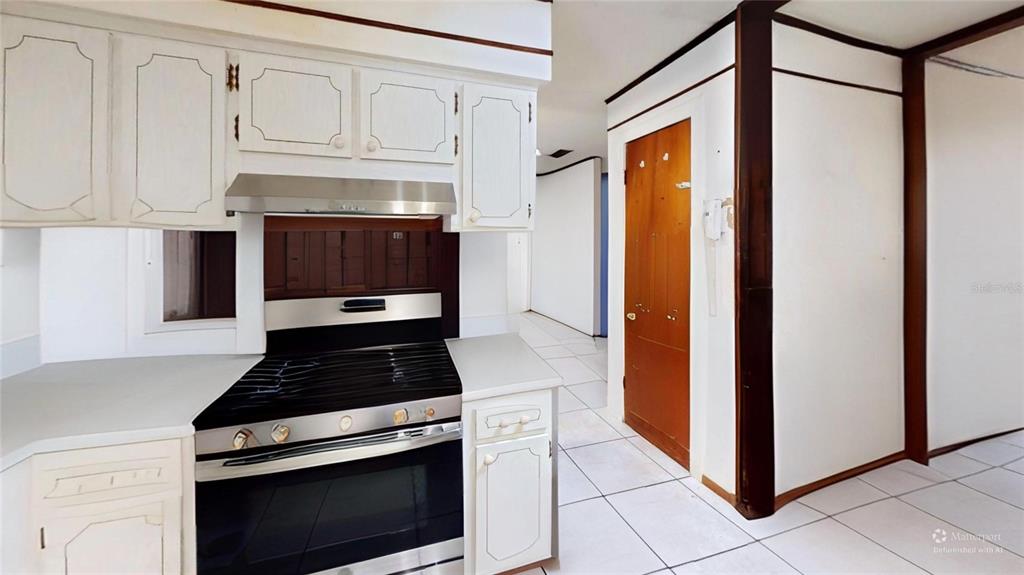 A kitchen features white cabinets, a stainless steel range, and white tile flooring — 395 BACARDI DRIVE, MERRITT ISLAND, FL